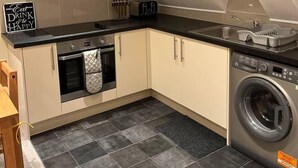 A compact kitchen with a built-in oven, a washing machine, and a toaster. - Central Location 2-bed Apartment in Maidstone (Maidstone)