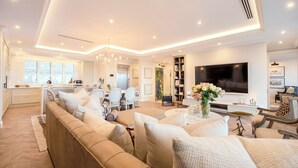 A modern living room with a sofa, TV, and a dining area with chairs and a table. - The Weinberg Urban Pods (Windhoek)