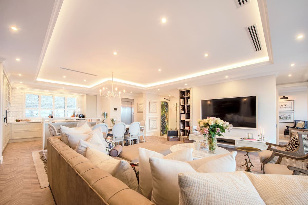 A modern living room with a sofa, TV, and a dining area with chairs and a table.