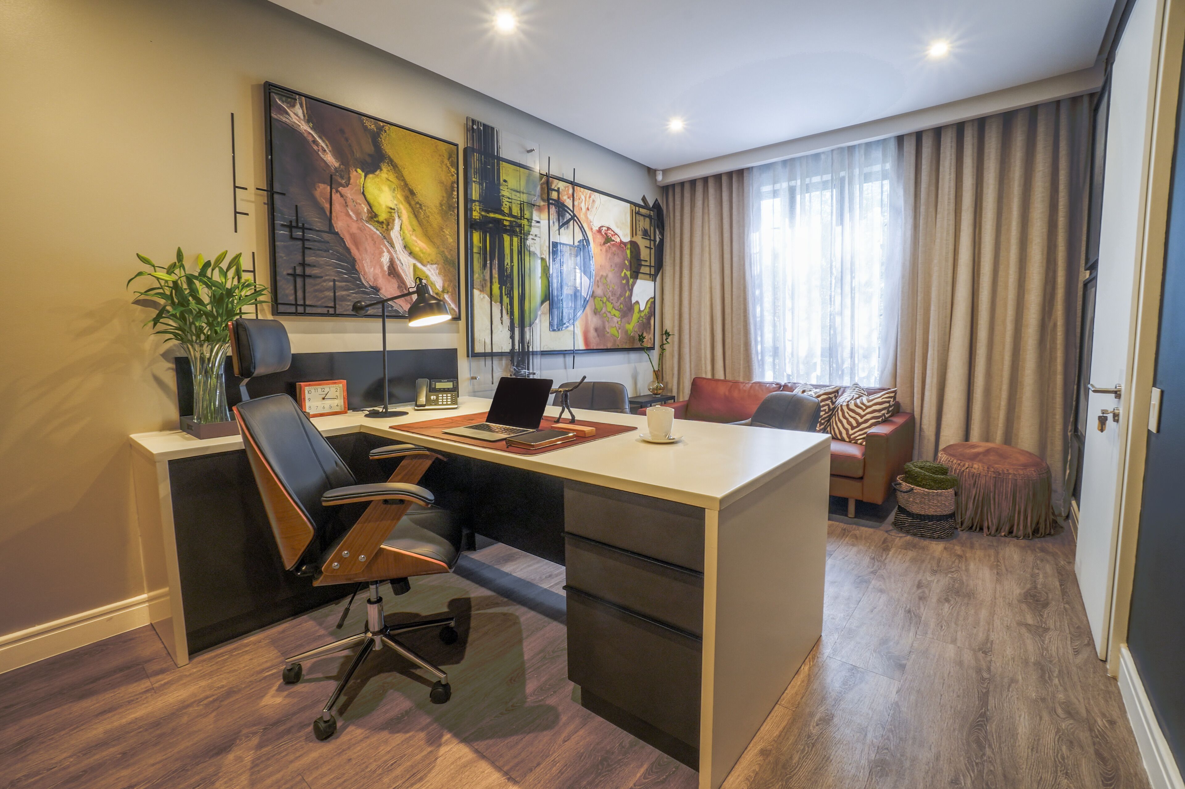 Un espacio de oficina moderno con un escritorio, una silla de oficina y un cuadro grande en la pared.
