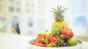 A plate of fresh fruits including strawberries, grapes, blueberries, a pineapple, and an apple.