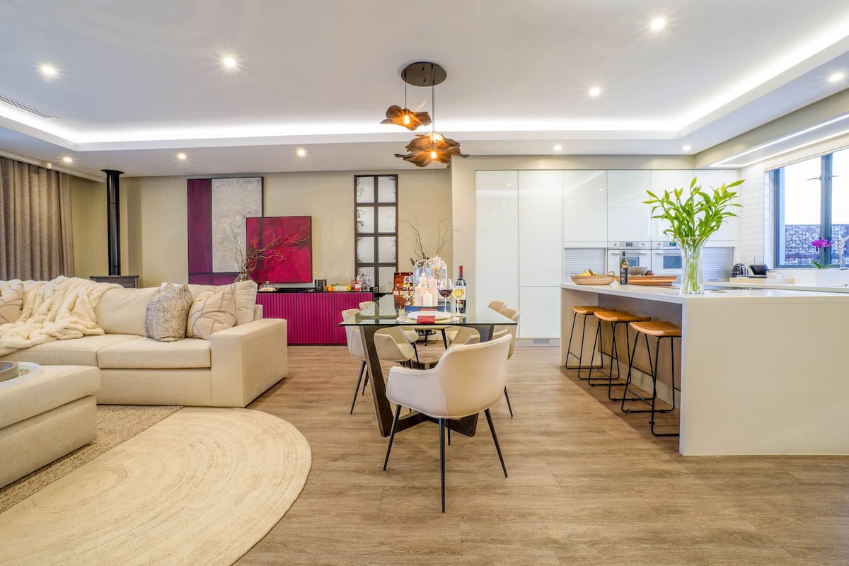 A modern living room with a sofa, a dining table, and a kitchen area with a bar.
