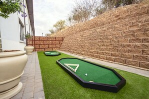 A mini-golf setup with two putting greens and a brick wall in the background. - The Weinberg Urban Pods (Windhoek)