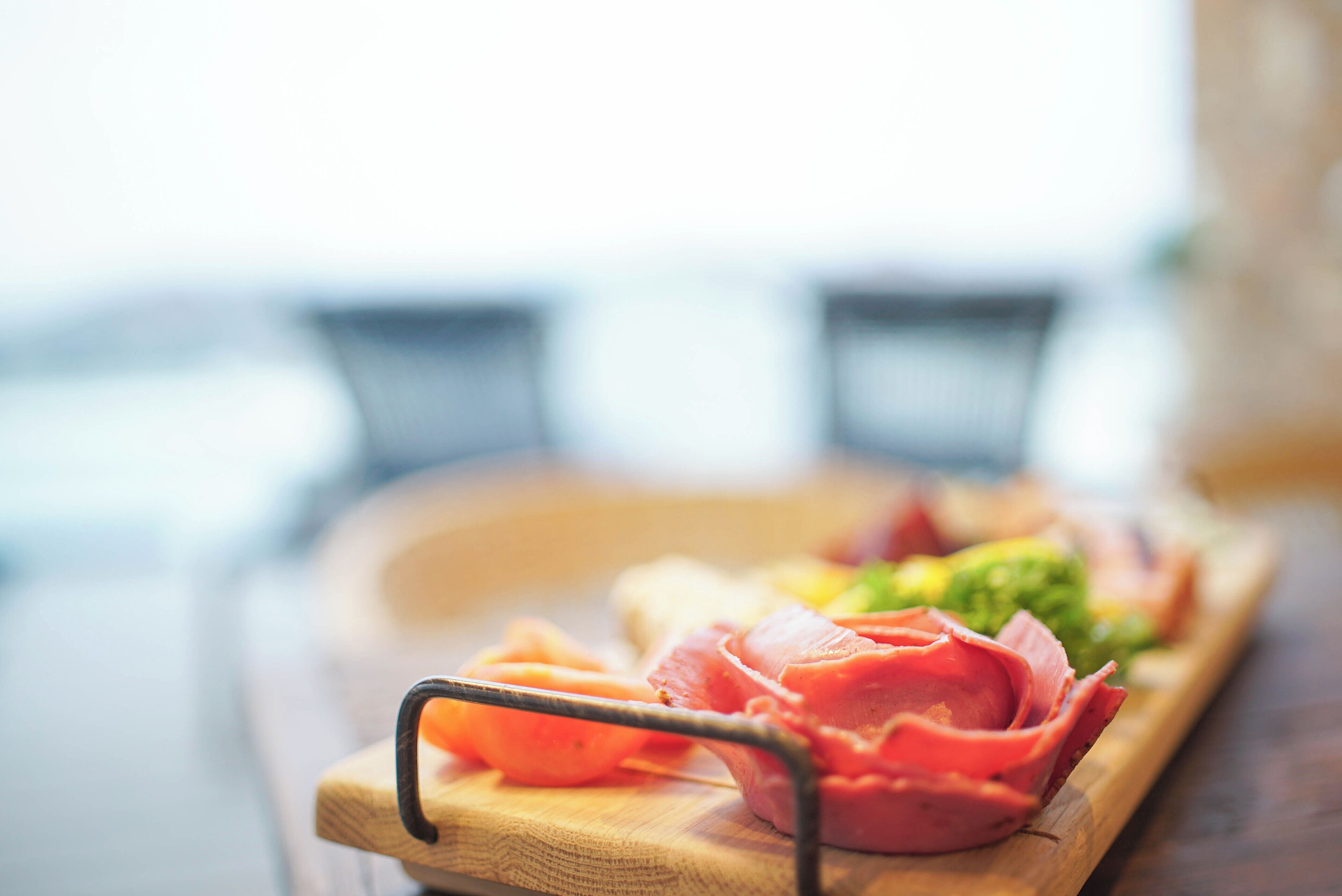 Una tabla de madera con diversos alimentos, como carne y verduras cortadas, sobre una mesa de madera.