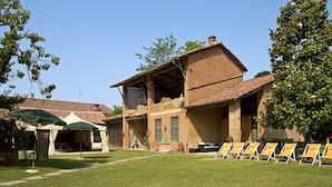 A rustic building with a brick exterior, a tiled roof, and a grassy lawn with sun loungers. - tenuta la violina (Asti)