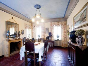 A dining room with a fireplace, a chandelier, and floral wallpaper. - tenuta la violina (Asti)