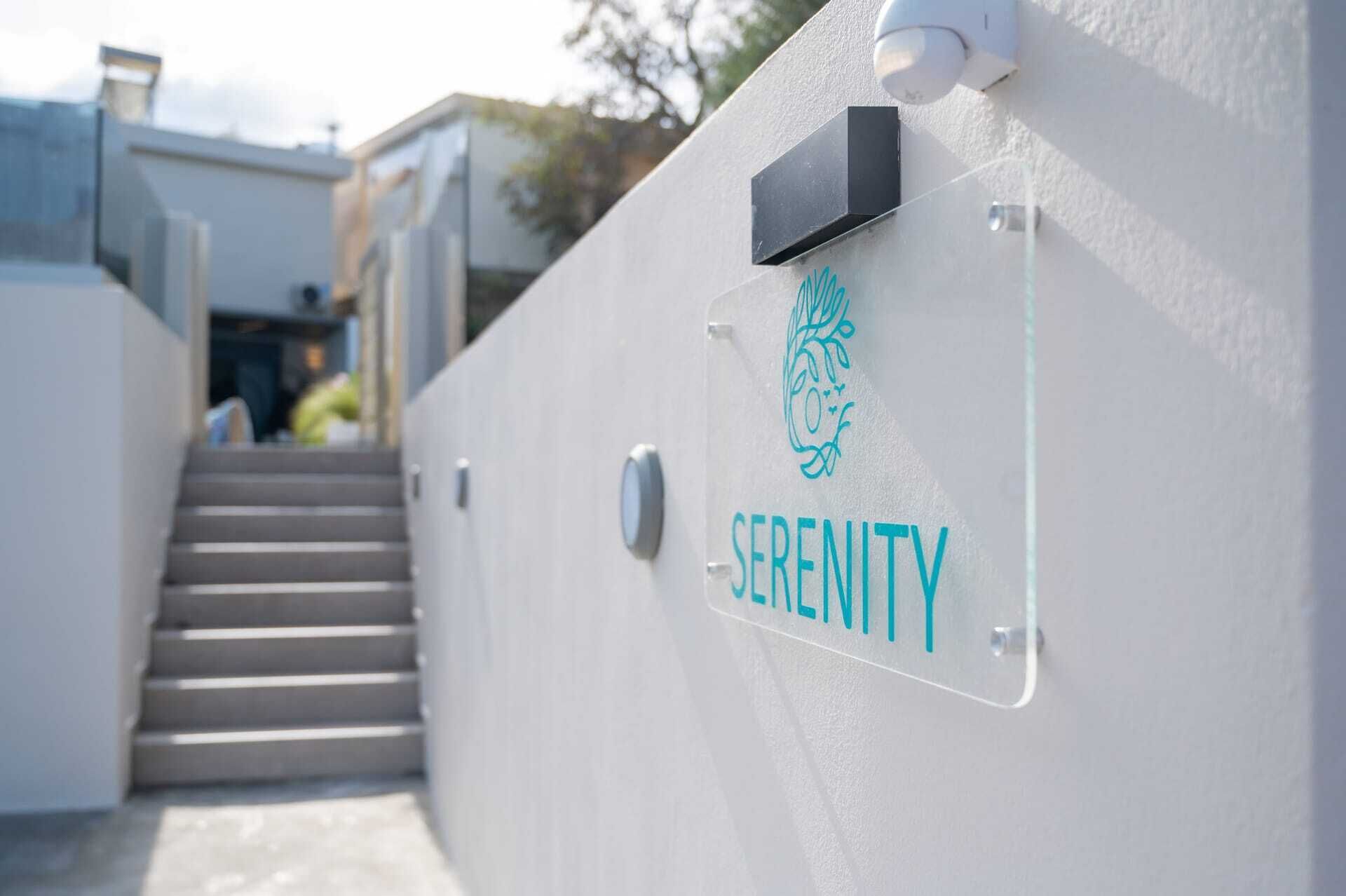 Une enseigne avec le mot « SÉRÉNITÉ » et un logo sur un mur blanc.