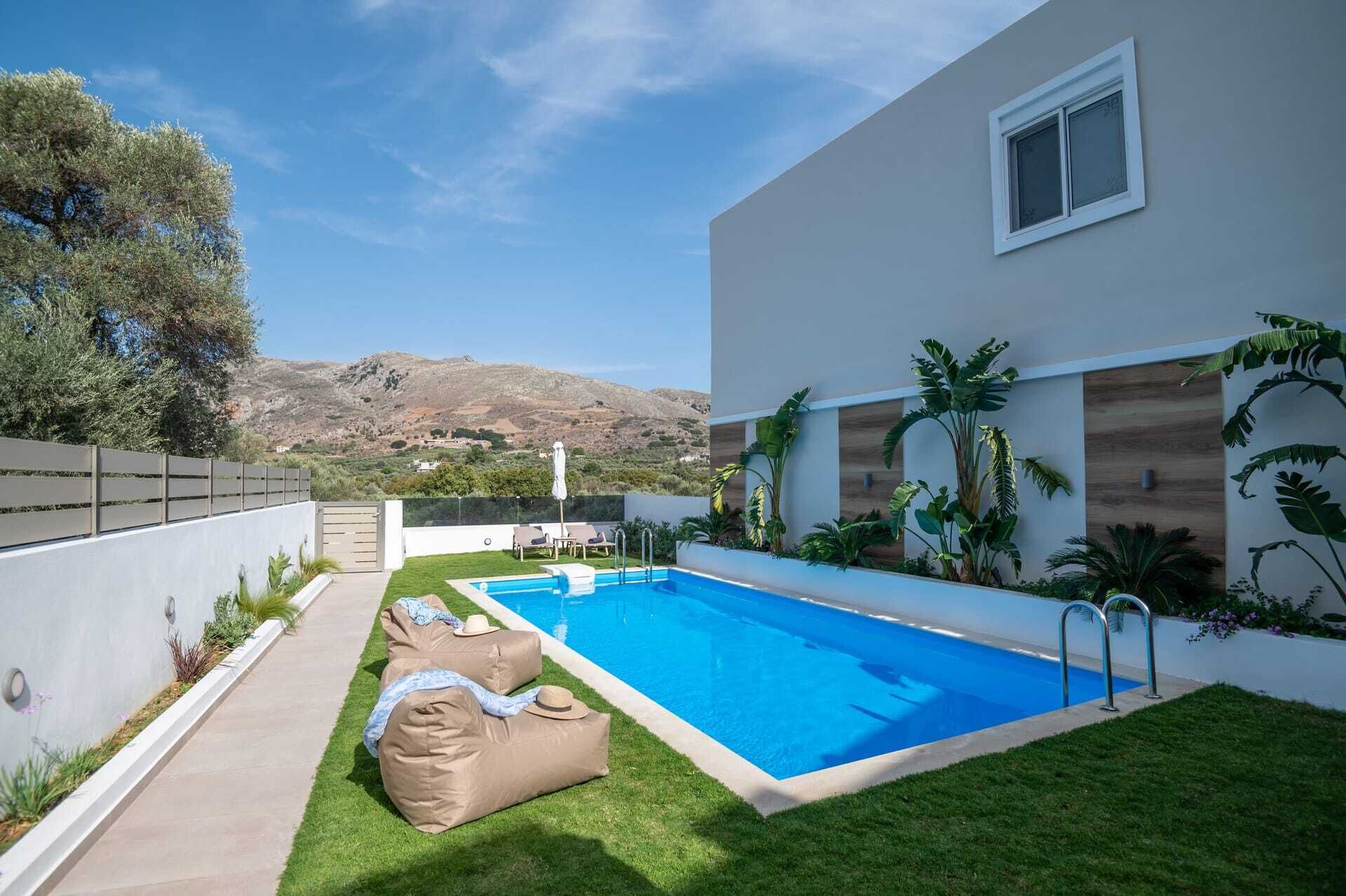 A modern pool area with a clear view of the surrounding landscape, including hills and a fence.