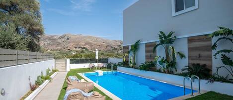 A modern pool area with a clear view of the surrounding landscape, including hills and a fence.