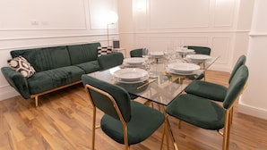 A dining area with a glass table, green upholstered chairs, and a green sofa. - La Gioberta Holiday Home (Roma)