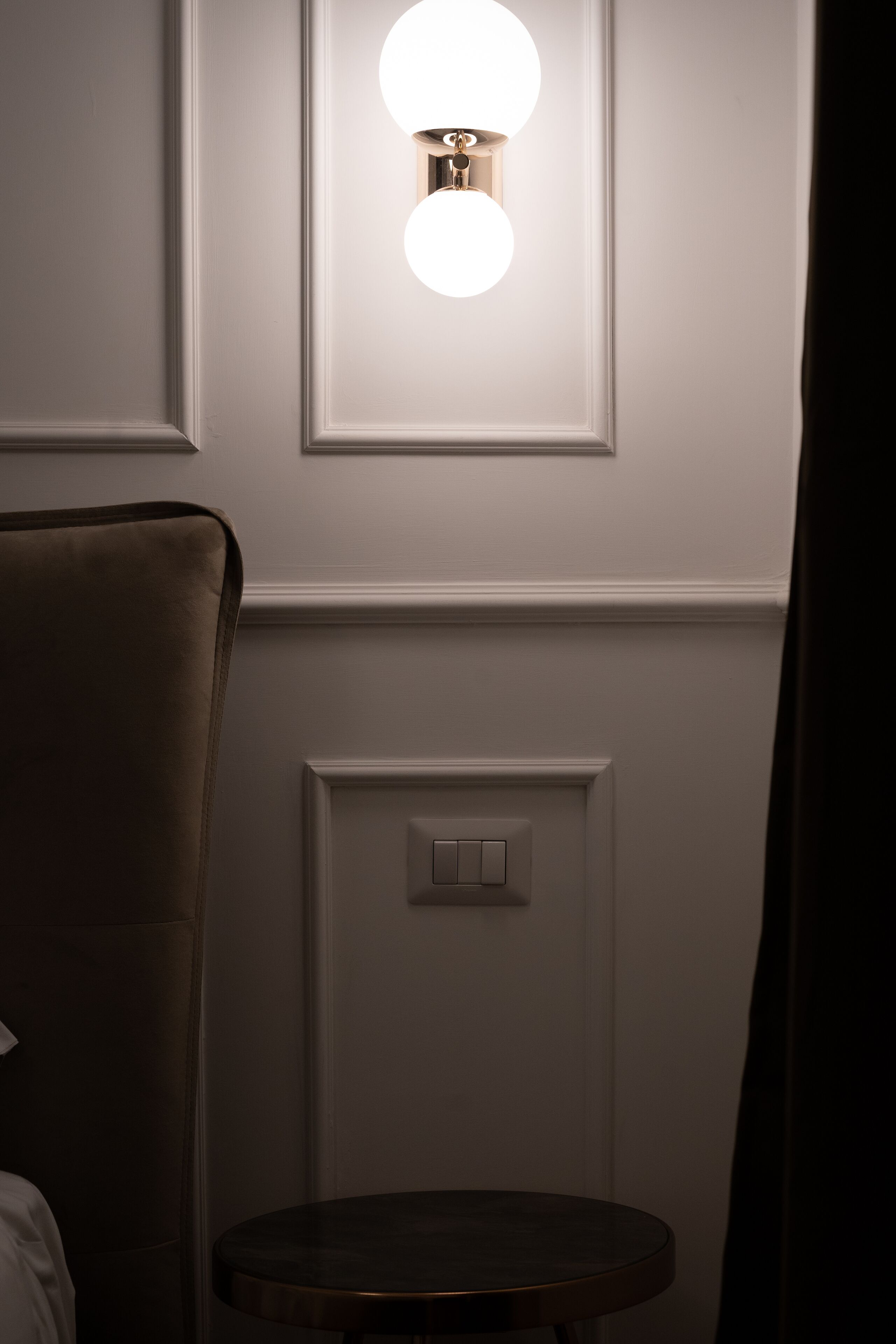 Una habitación con una mesa redonda, una lámpara fijada a la pared y un interruptor de luz.