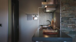 A modern kitchen with a stainless steel countertop, a gas stove, and a stone backsplash.
