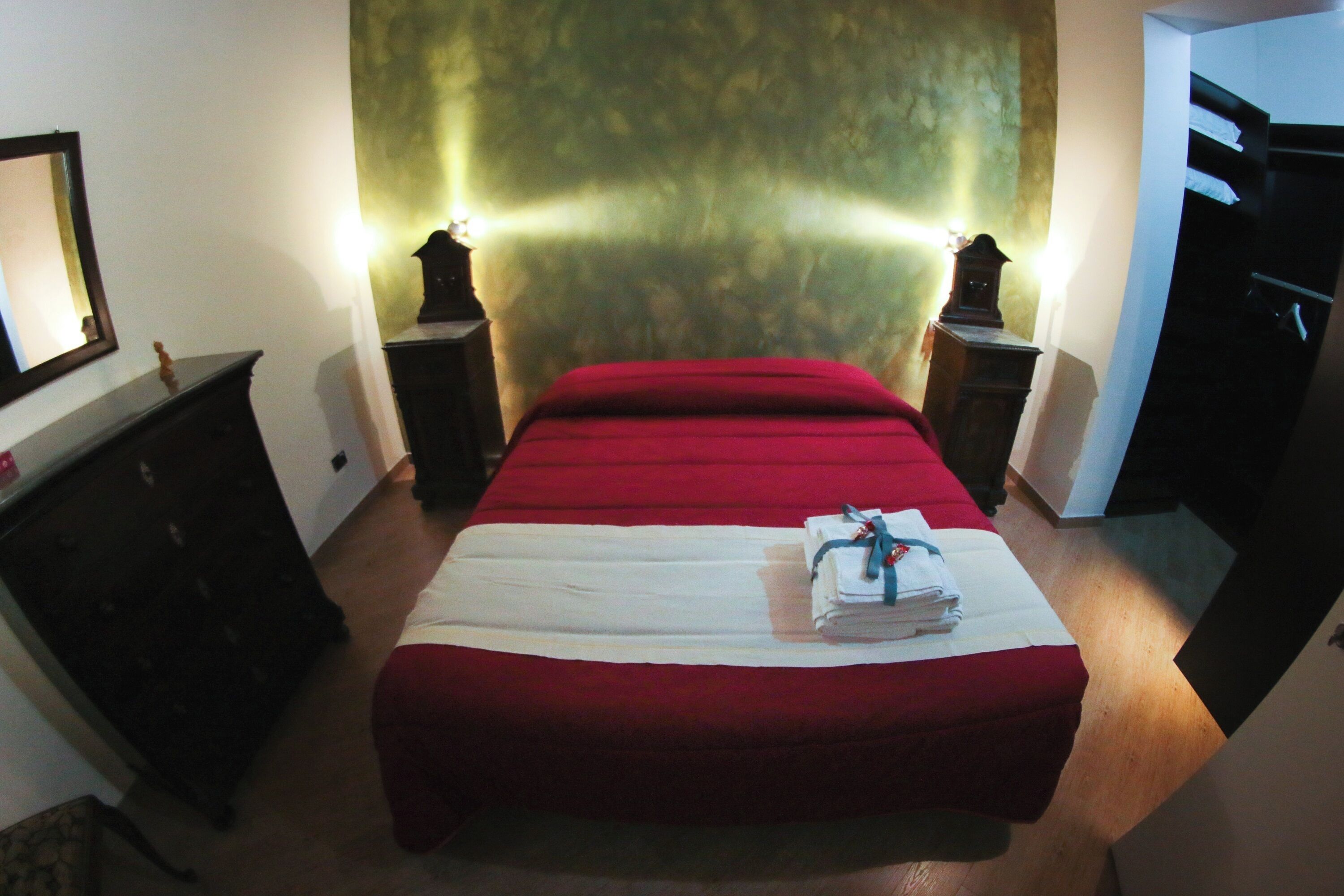 Ein Schlafzimmer mit Bett, Schminktisch, Nachttisch und Spiegel.