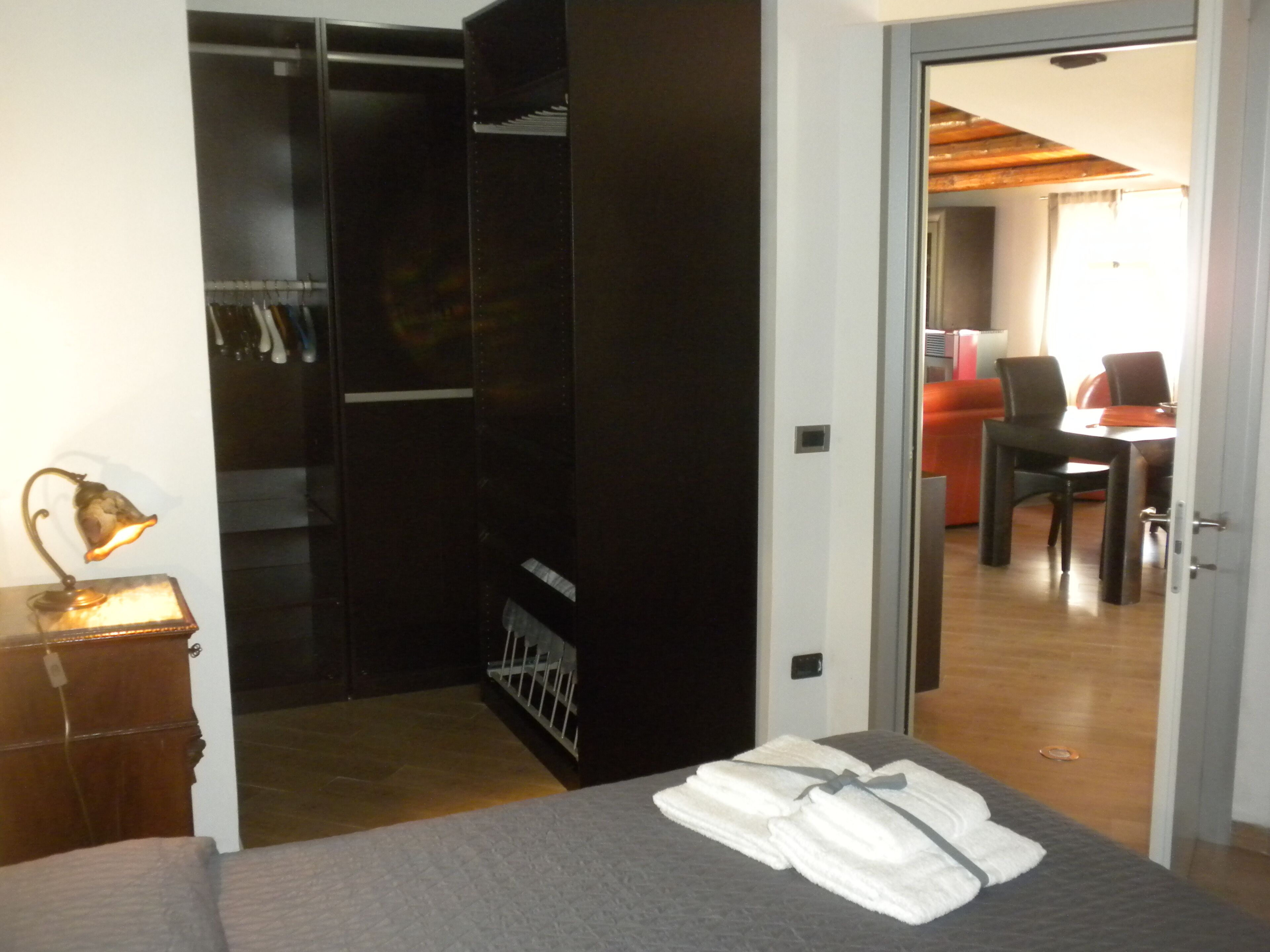 Una camera d'albergo con un letto, un armadio, una scrivania con una sedia e un'area pranzo con tavolo e sedie.