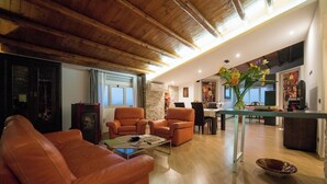 A spacious living room with leather sofas, a coffee table, and a dining area with a kitchen in the background.