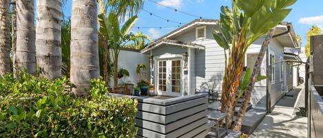 A house with a deck, surrounded by palm trees and a garden.