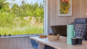 Een knus ingerichte kamer met een houten tafel, een fruitschaal, een groene mok en een bank met geruit kussens.
