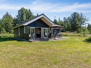 Een klein, gelijkvloers vakantiehuisje met een overdekt terras, een schuifpui en een terras met tuinmeubilair.