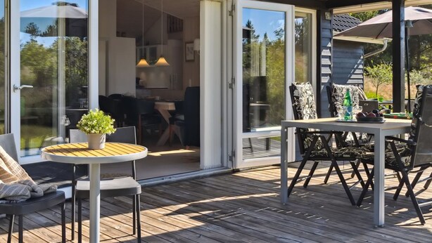 Een moderne eethoek buiten met een houten terras, een ronde tafel en stoelen.
