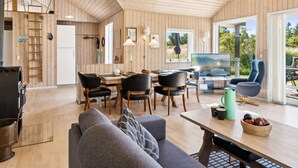 Een ruime woonkamer met een eettafel, stoelen, een bank, een televisie en een open haard.