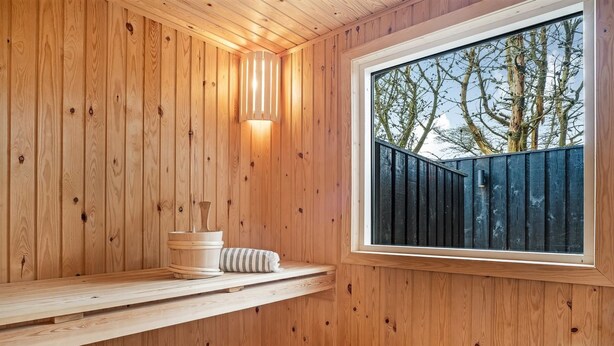 Un sauna en bois, doté de bancs et d’une fenêtre.