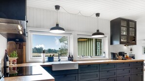 Une cuisine moderne dotée d’un grand îlot central, de meubles de couleur sombre et de luminaires suspendus.