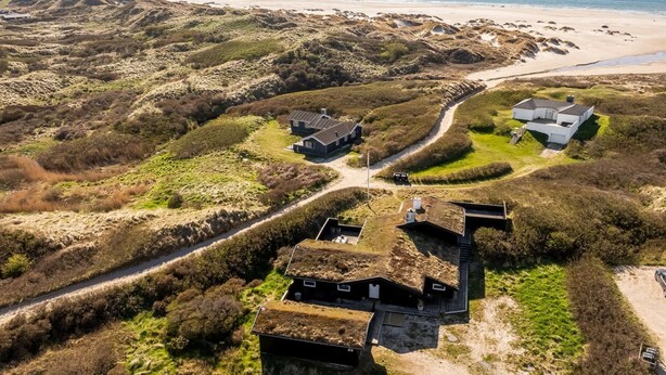 Vista aèria d'una propietat costera amb diverses edificacions, incloent-hi una casa amb teulada verda, una casa blanca i una construcció amb teulada fosca.