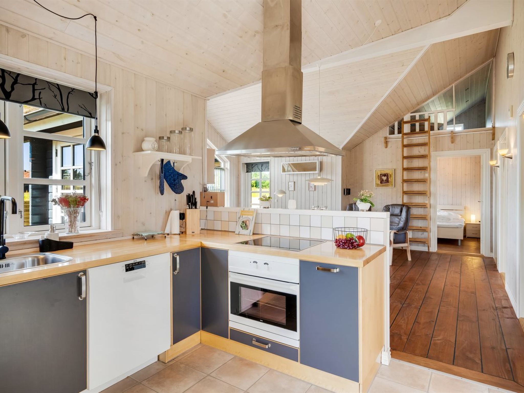 Cocina moderna con una isla central, horno empotrado y vistas al dormitorio contiguo.