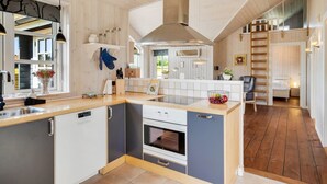 A modern kitchen with a central island, built-in oven, and a view to the adjacent bedroom.