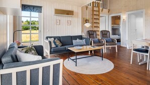 A spacious living room with a wooden ceiling, a sofa set, a coffee table, and a view of the outdoors.