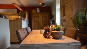 Uma área de refeições com mesa de madeira, cadeiras de couro e plantas em vasos.