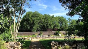 Um caminho no jardim leva a um espaço de estar com paredes de pedra e cerca de madeira.