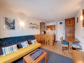 A compact living space with a sofa, a small coffee table, a dining table with chairs, a kitchen area, and a wooden cabinet. - Functional studio near slopes and shops, balcony and mountain corner (Montvalezan-La Rosière)