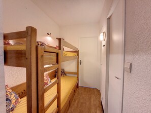 A room with bunk beds, a door, and a light switch on the wall.