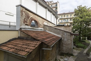 Stunning corner building with a brick facade and red-tiled roof, featuring a charming arched window and beautifully maintained garden.