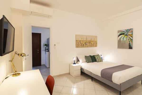 Cozy retreat with a made bed, bedside table, and wall-mounted TV.