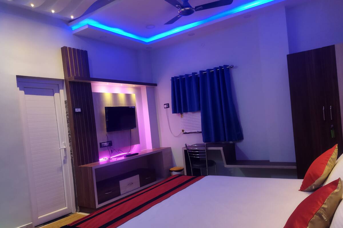 A modern bedroom with a bed, a TV, and a desk area.
