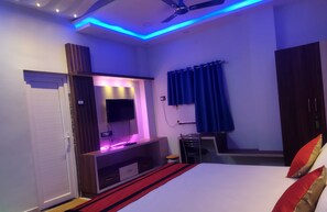 A modern bedroom with a bed, a TV, and a desk area. - G P Guest House And Banquet Hall (Gaya)