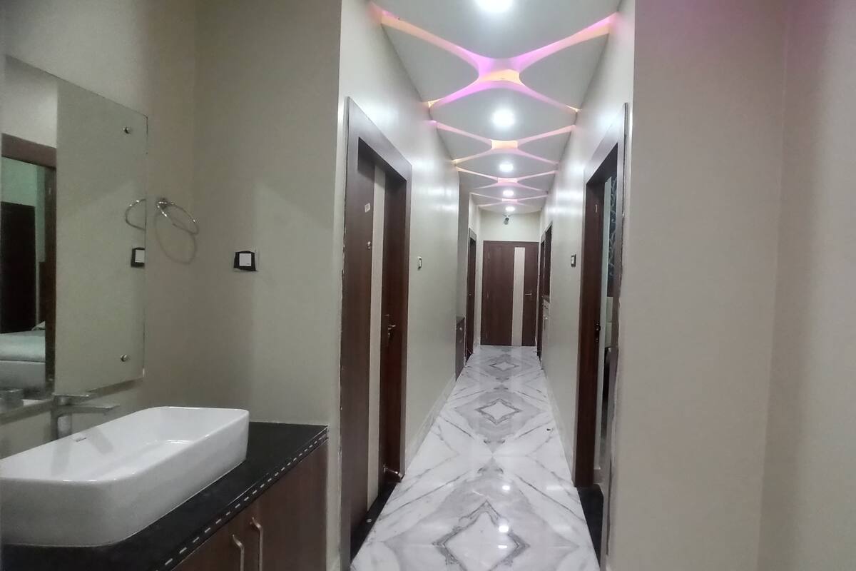 A hallway with a marble floor, a sink on the left, and doors on both sides.