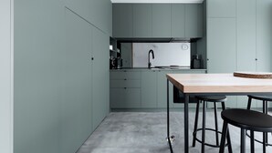 A modern kitchen with grey cabinets, a wooden table, and black stools.