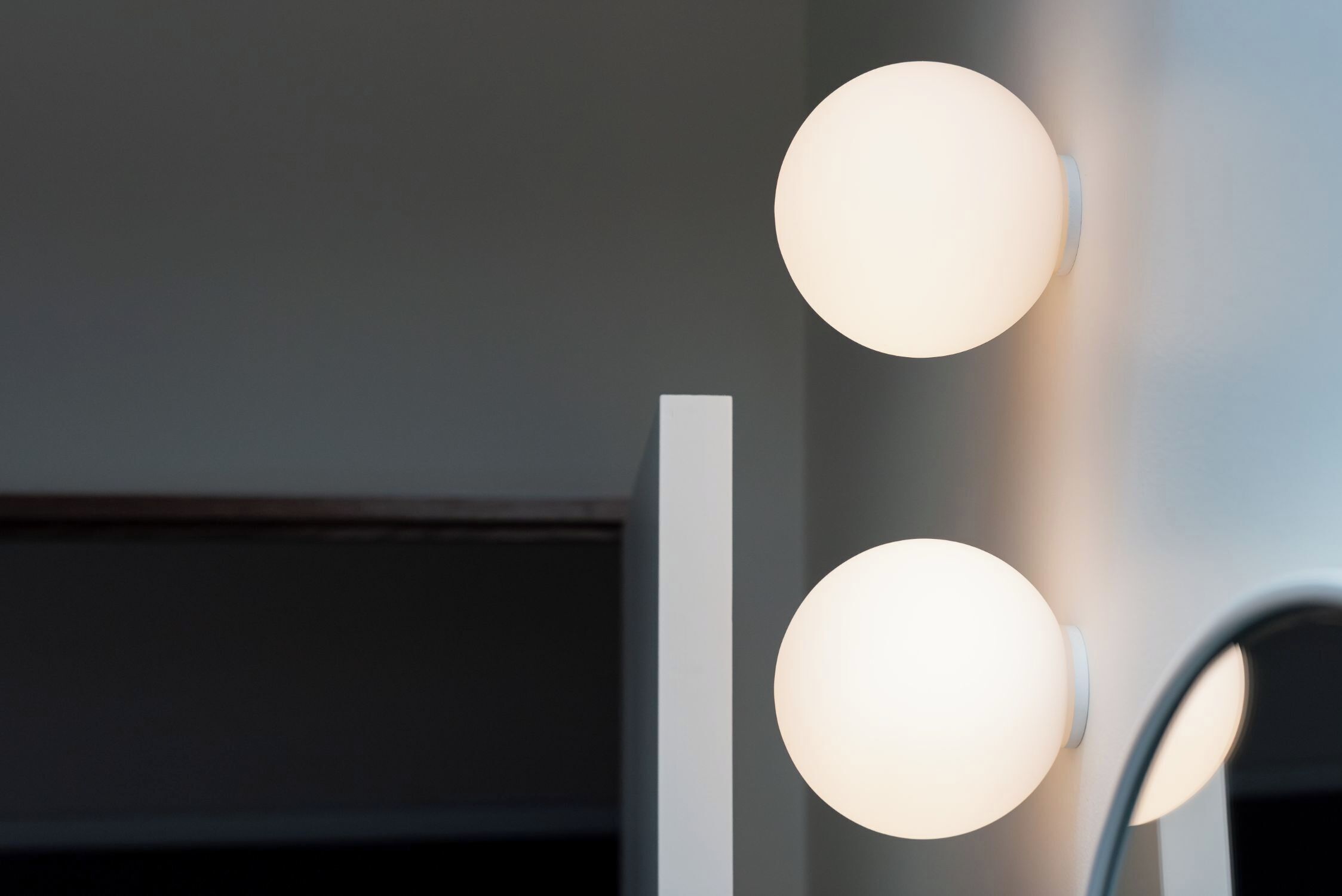 Un intérieur moderne avec deux lampes sphériques fixées au mur et un panneau vertical blanc.