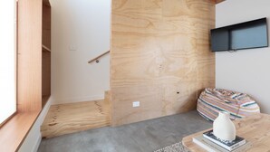 A modern room with a wooden floor, a built-in bench, a flat-screen TV, and a window with a view.