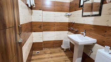 A bathroom with wooden panel walls, a white sink, a toilet, and a shower area.