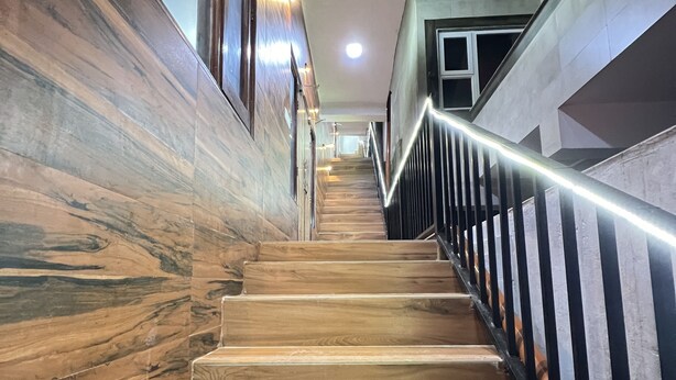 Una escalera de madera con barandilla de metal, que conduce a un piso superior.