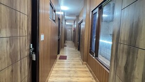 Un pasillo largo y estrecho con paredes y piso de madera. Hay puertas a ambos lados y un tapete rojo sobre el piso.