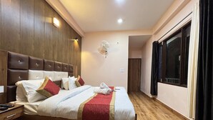 Habitación de hotel con una cama grande, cabecera de madera y una ventana con cortinas.