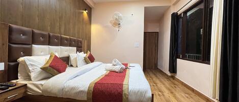 Habitación de hotel con una cama grande, cabecera de madera y una ventana con cortinas.