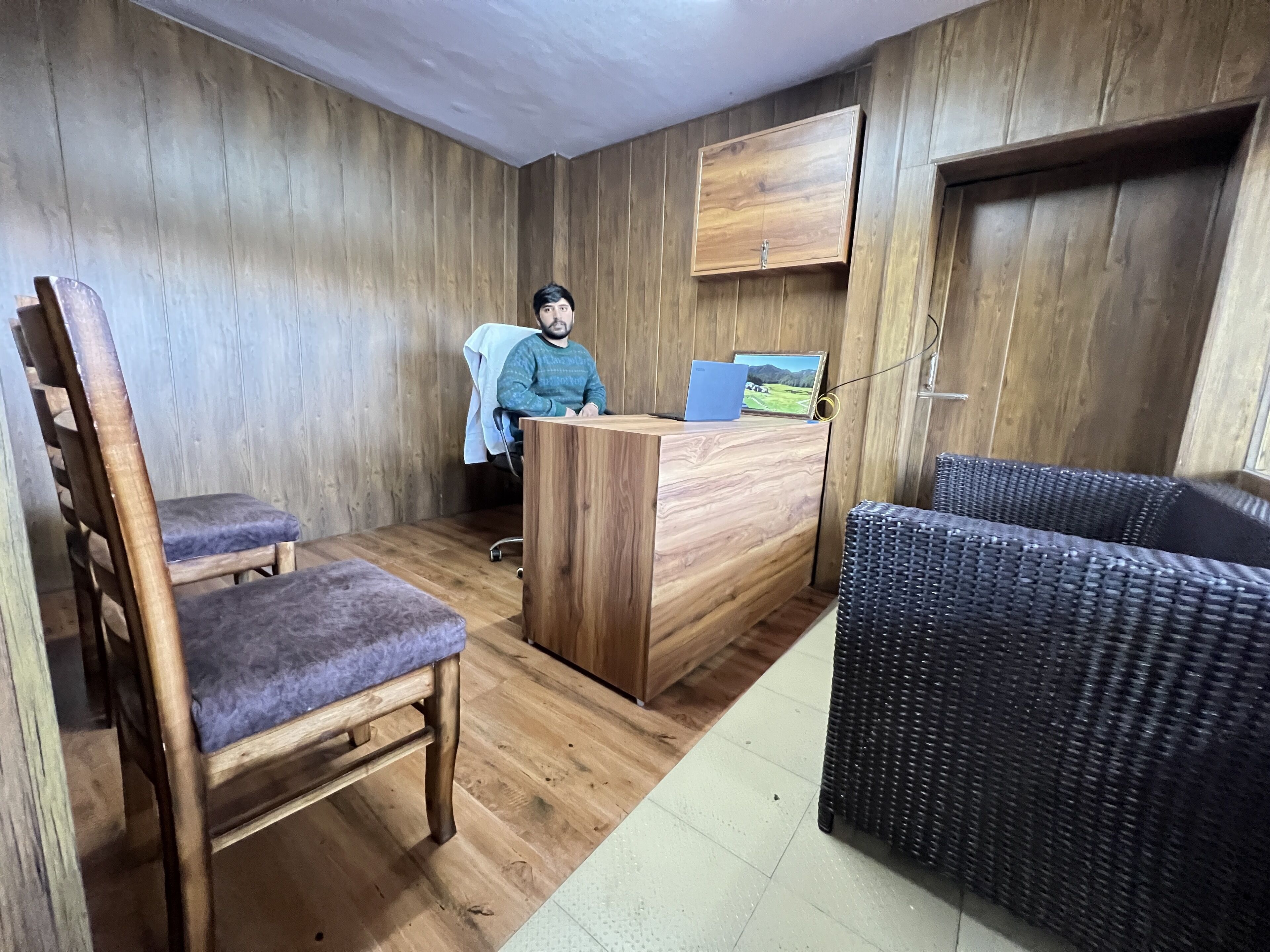 A room with a wooden desk, a chair, a sofa, and a bed.