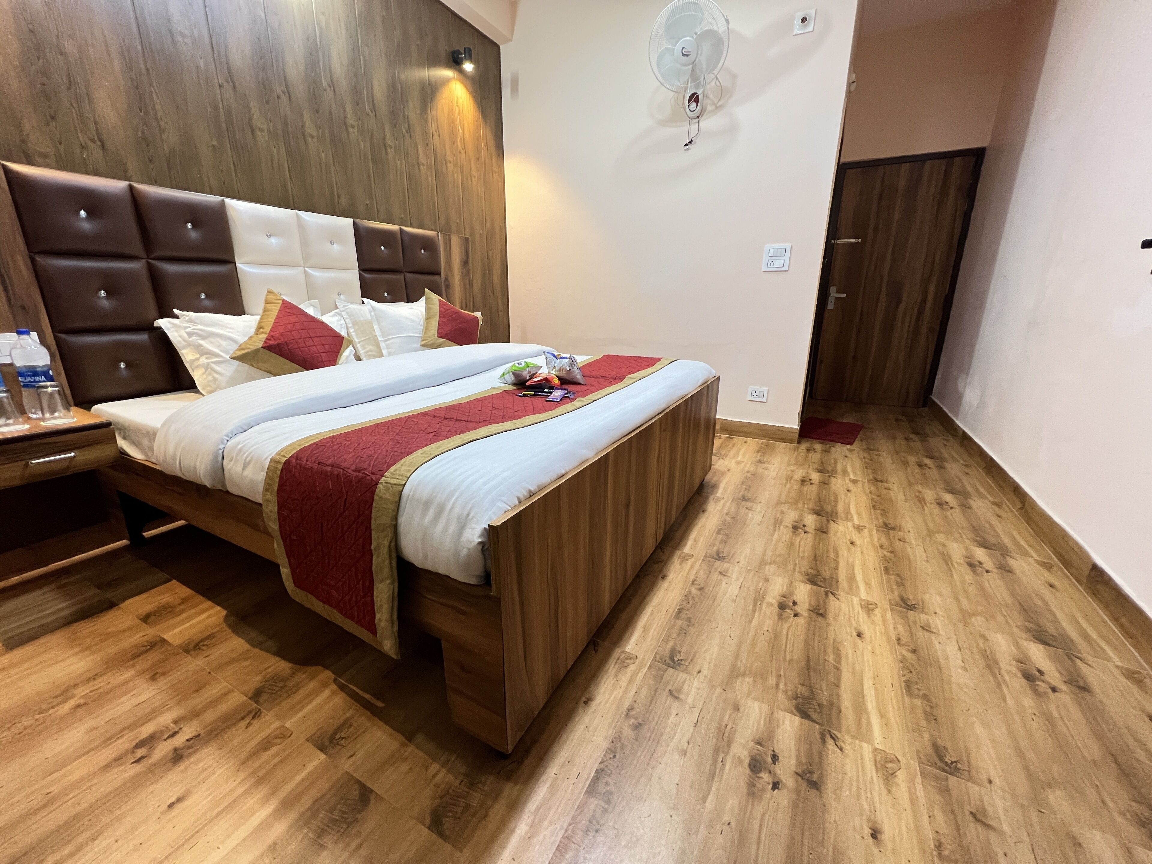 A bedroom with a wooden bed frame, a headboard, and a bedside table with a water bottle.