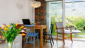 Ein stilvoller Essbereich mit einem Holztisch, blauen und schwarzen Stühlen, einem Laptop und einer Blumenvase.